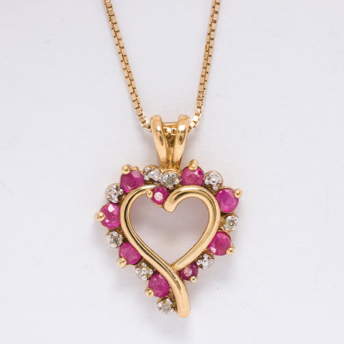 A ruby, diamond, and sterling silver pendant necklace: A ruby, diamond, and sterling silver pendant necklaceDesigned as a heart, set with nine round-cut rubies and three round-cut diamonds; pendant length: 7/8 in; chain length: 18 in; 4.70 grams