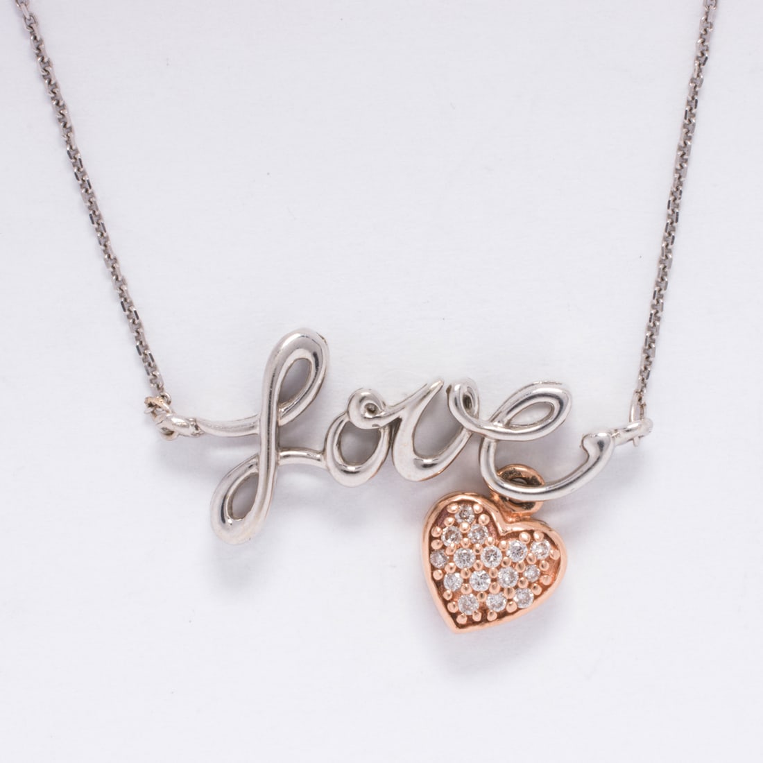 A diamond and 14k bi-color gold necklace: A diamond and 14k bi-color gold necklaceDesigned the word "Love", accented by a diamond and 14k yellow gold charm; length: 19 in; 3.55 grams