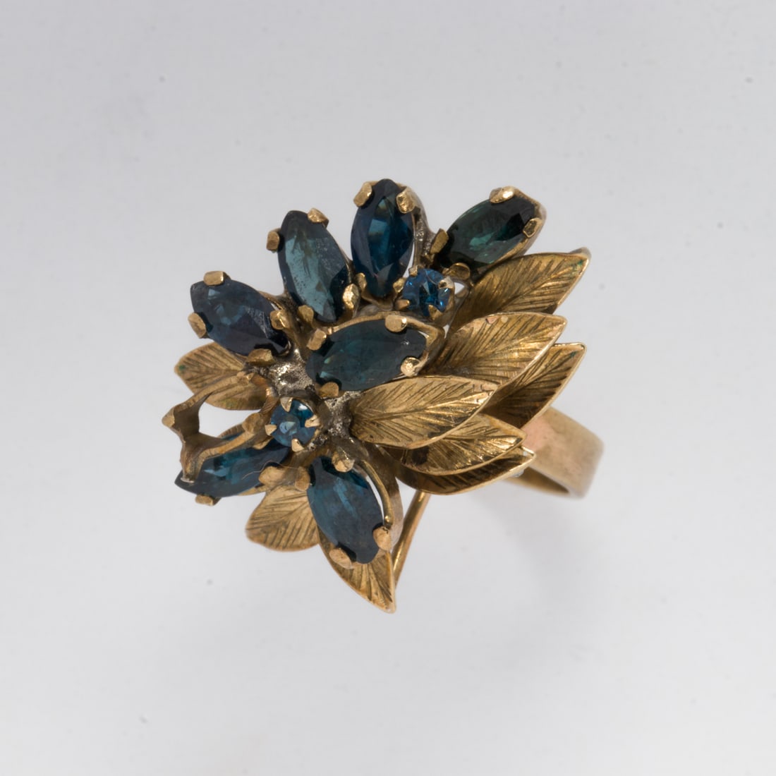 A sapphire and 10k gold ring: A sapphire and 10k gold ringDesigned as leaves, set with seven marquise-cut and two round-cut sapphires weighing a total of 1.24 carats; size 6; 5.05 grams