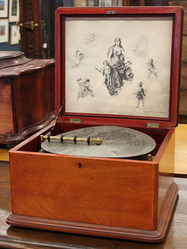 Regina music box: Regina music box, having a hinged mahogany case opening to the lithographic panel and the comb player accomodating 11" discs, 9.5"h x 14"w x 13"d
