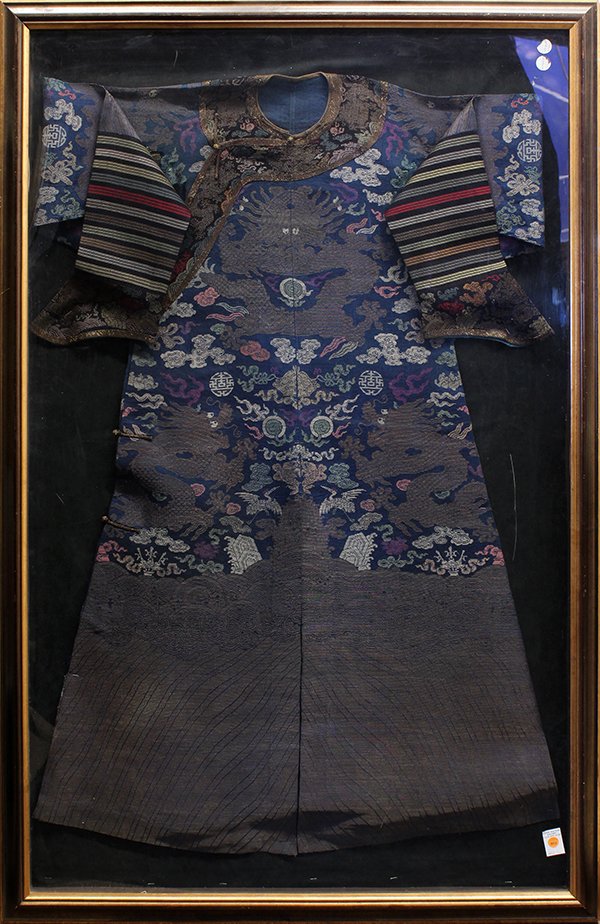 Chinese Blue Dragon Robe, Jifu: Framed Chinese blue silk gauze robe (jifu), woven with meandering gilt dragons amid colored clouds, shou medallion, Buddhist treasures and auspicious emblems, above a gilt lishui border, overall (fram