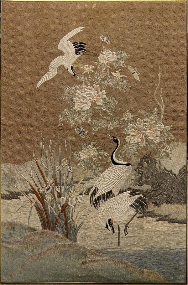 Japanese Embroidery of Cranes: Japanese embroidered hanging, of three cranes amid peonies and iris executed in satin stitches, silhouetted on a couched spiral ground, overall (with frame): 84.25"h x 42.25"w