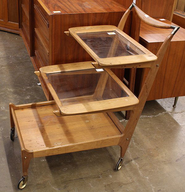 Danish Modern serving cart: Danish Modern serving cart, executed in teak circa 1960, the tiered form with removable trays resting on a cantilevered support terminating at the bottom shelf and rising on casters, 35"h x 19"w x 36"