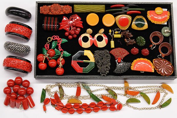 Collection of bakelite jewelry items: One tray of bakelite jewelry items including a link chain bracelet with cherry blossom charms; Two broken bangle bracelets, one with rhinestones; One broken bracelet with round and rectangular red bak