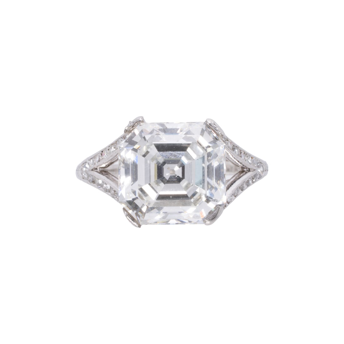 An art deco diamond and platinum ring: An art deco diamond and platinum ringFeaturing a cut-cornered square step-cut diamond weighing 4.92 carats, within platinum mounting set with 26 single-cut diamonds and accented by etched scrollwork;