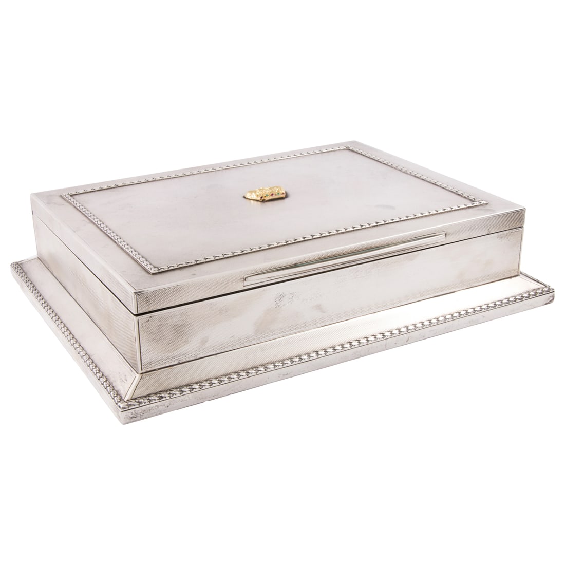 A British Asprey of London Sterling Cigar Box: An English Asprey of London sterling cigar box, the cover embellished with a gilt crown set with rubies and emeralds centered by an acanthus leaf border, the hinged top opens to an inscription to the