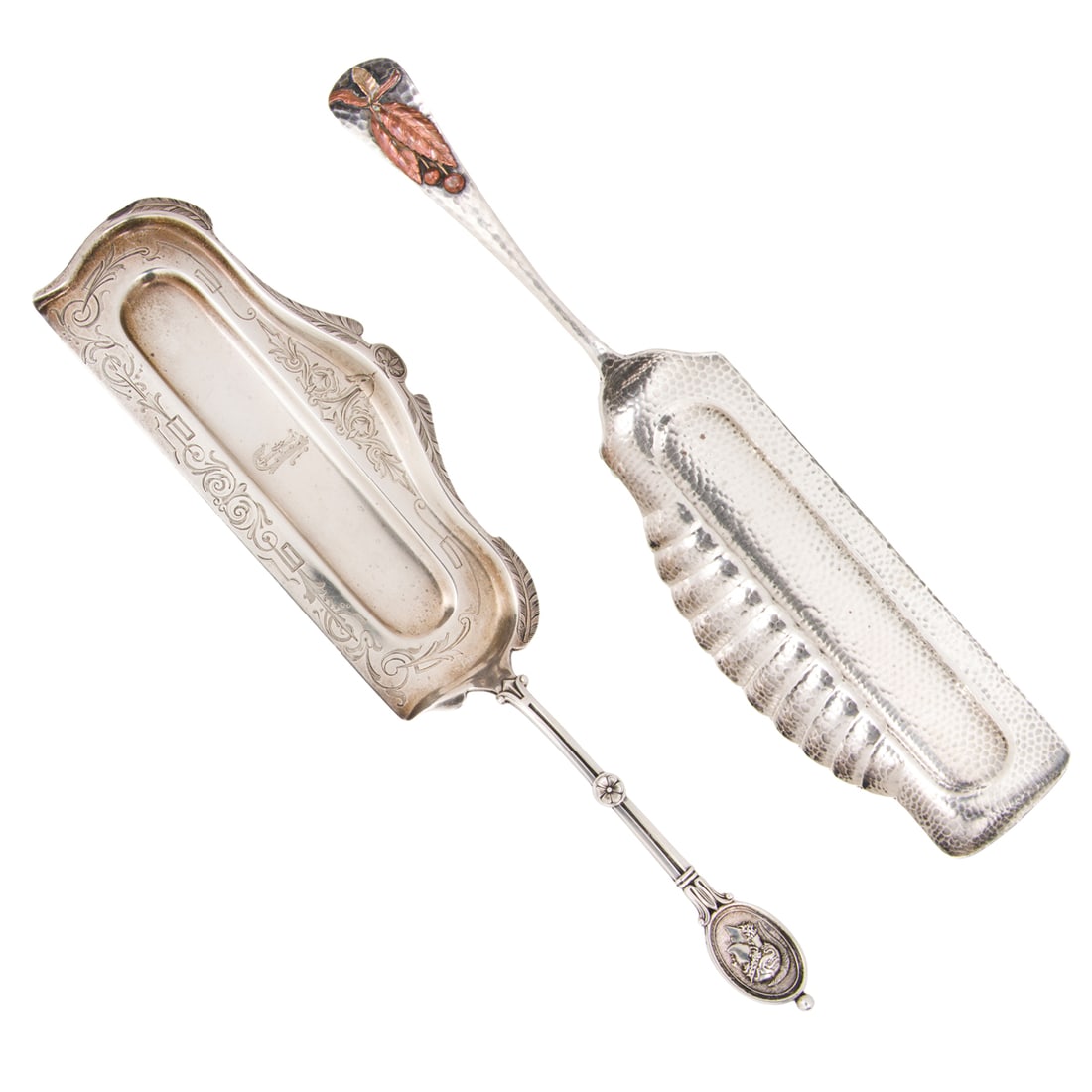 Two Sterling Crumbers including Gorham Mixed Metal: Two American sterling crumbers, comprising (1) Gorham example with applied copper and brass leaf and berry motif, 12.5"l and (1) Starr & Marcus retailed with Neoclassical motif, monogrammed, 13",