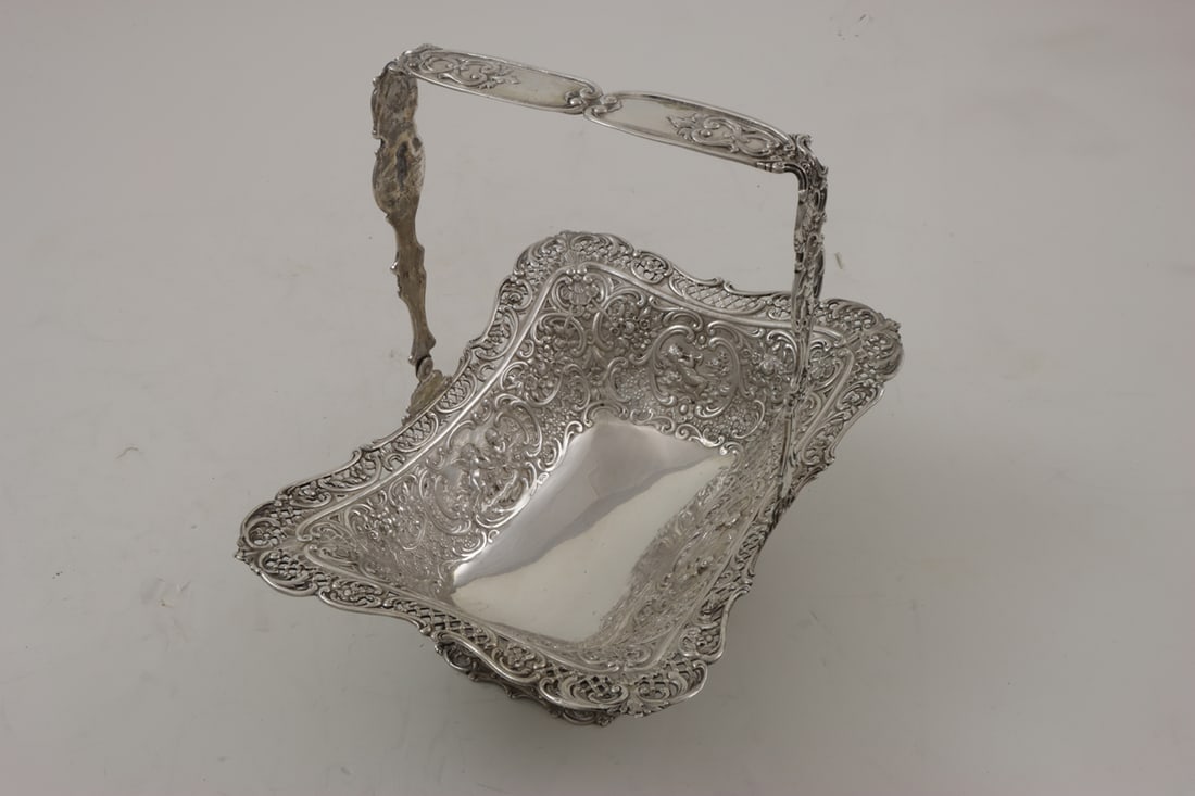 A Continental 800-Silver Handled Basket: A Continental 800-silver handled basket, extensive repousse decoration throughout with putto reserves, c-scrolls and botanical motif, 11"w, 20.59 troy oz
