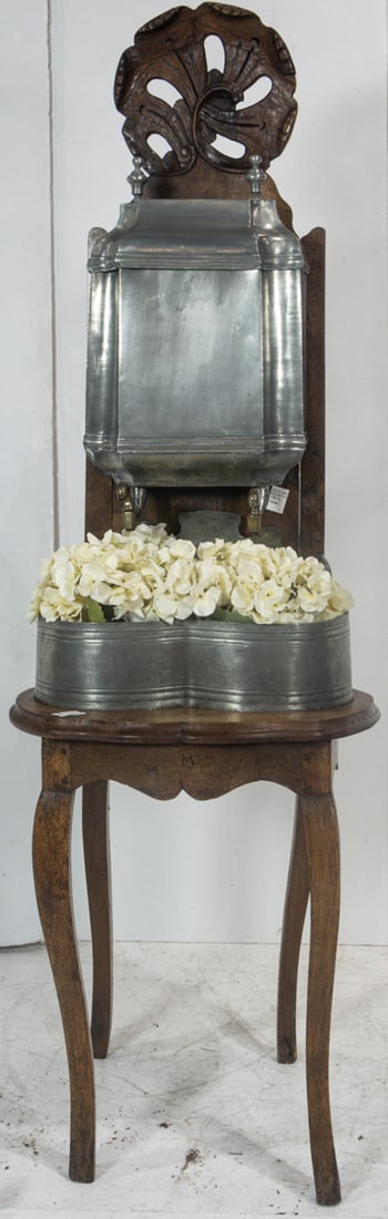 A French pewter lavabo on stand last quarter 18th century: A French pewter lavabo on stand last quarter 18th century, the carved walnut back panel ornamented with acanthus leaves, and a bold central shell crest in the Rococo taste, retains original pewter