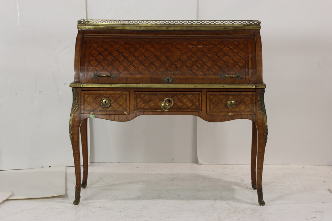 A French marquetry decorated cylinder desk circa 1850: A French marquetry decorated cylinder desk circa 1850, having a reticulated gallery top above the barrel top opening to the fitted interior and original leather writing surface, and rising on