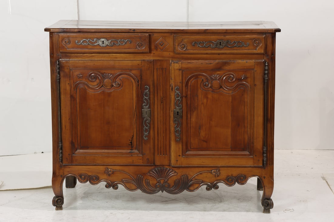 A French Louis XV Provincial buffet 18th century: A French Louis XV Provincial buffet 18th century, the hand carved case with panelled doors having large original escutcheons and opening to a fixed shelf, rising on upturned feet, 42.75"h x 53"w x
