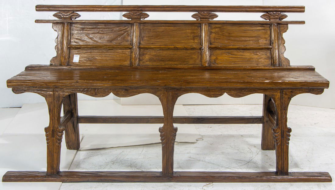 A carved primitive hall chair in the Asian taste: A carved primitive hall chair in the Asian taste, the contoured back continuing to the plank seat and rising on carved legs, 34.5"h x 67"w x 11.25" d