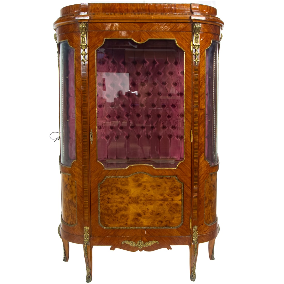A gilt bronze mounted vitrine: A gilt bronze mounted vitrine, the single door case with burl panels and a tufted silk lined interior, 68"h x 43"w x 18"d
