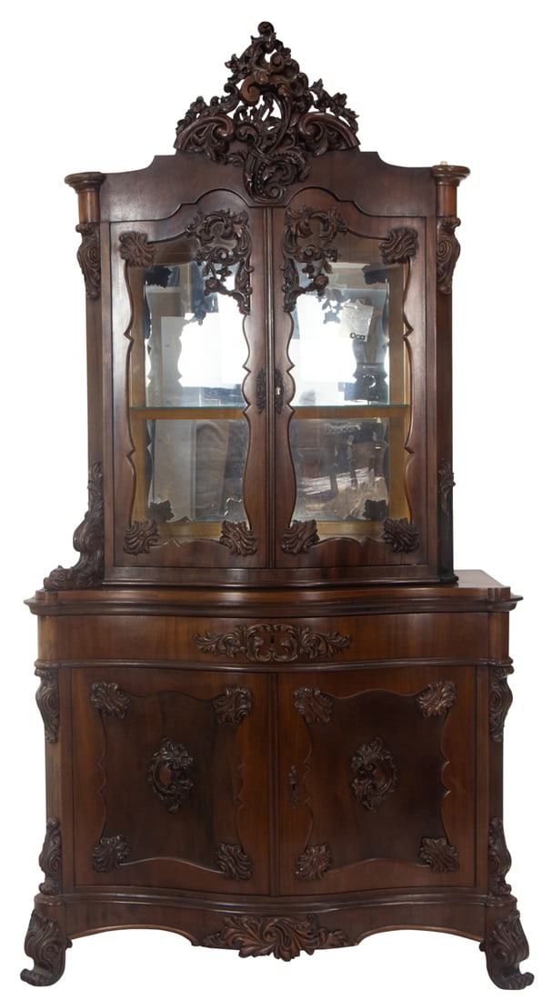 A Rococo Revival vitrine late 19th century: A Rococo Revival vitrine late 19th century, the serpentine case with two doors opening to the fixed shelf with mirrored back, above the lower case with carved panels, and rising on a molded base,