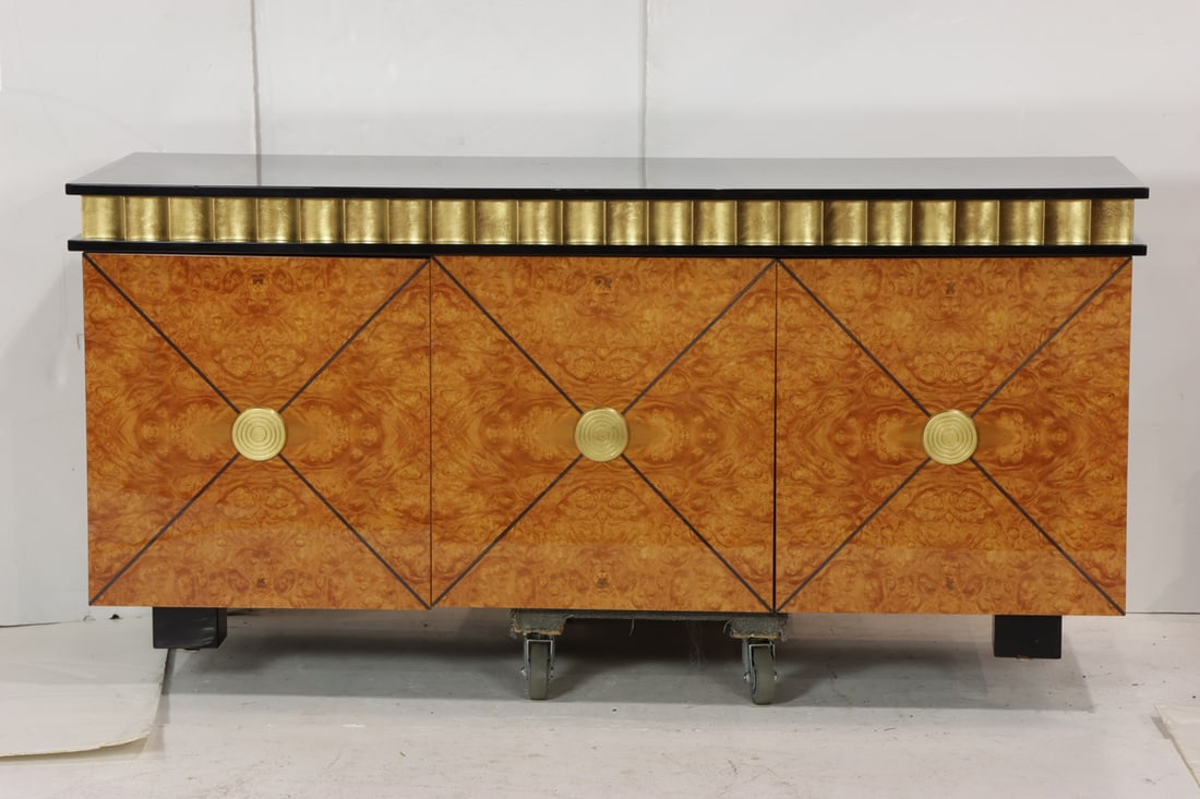 A parcel gilt and ebonized inlaid burlwood credenza: A parcel gilt and ebonized inlaid burlwood credenza, the highly figured burl case with gold leaf border and circular mounts, fitted with three doors, 34"h x 73.5"w x 24.75"d