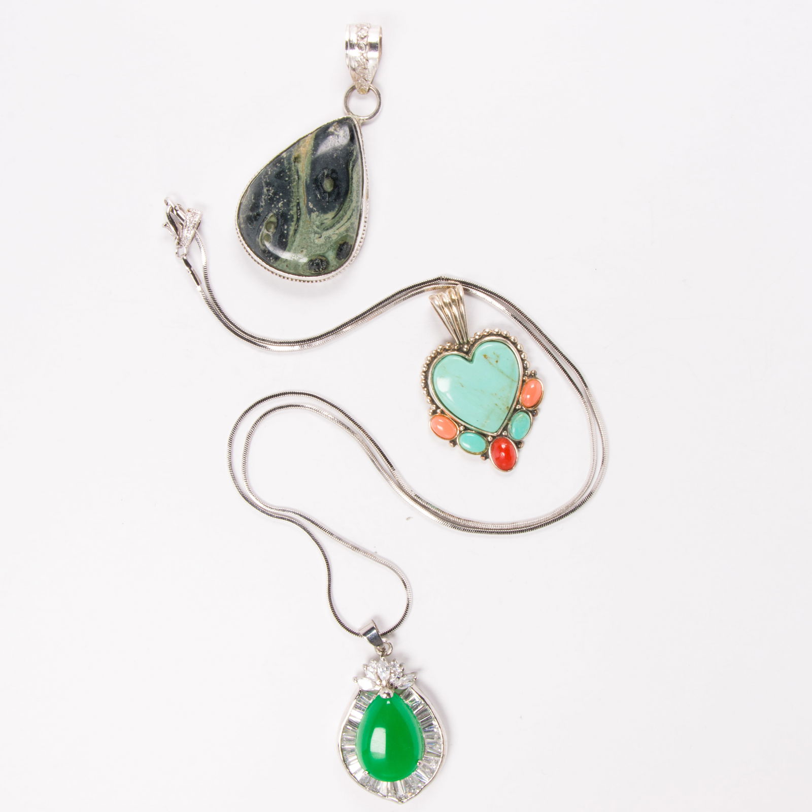 Three hardstone pendants and chain: Three hardstone pendants and chainComprising two pendants set with various hardstones, within silver bezels, together with a hardstone and silver-tone pendant set on silver-tone chain; chain length: