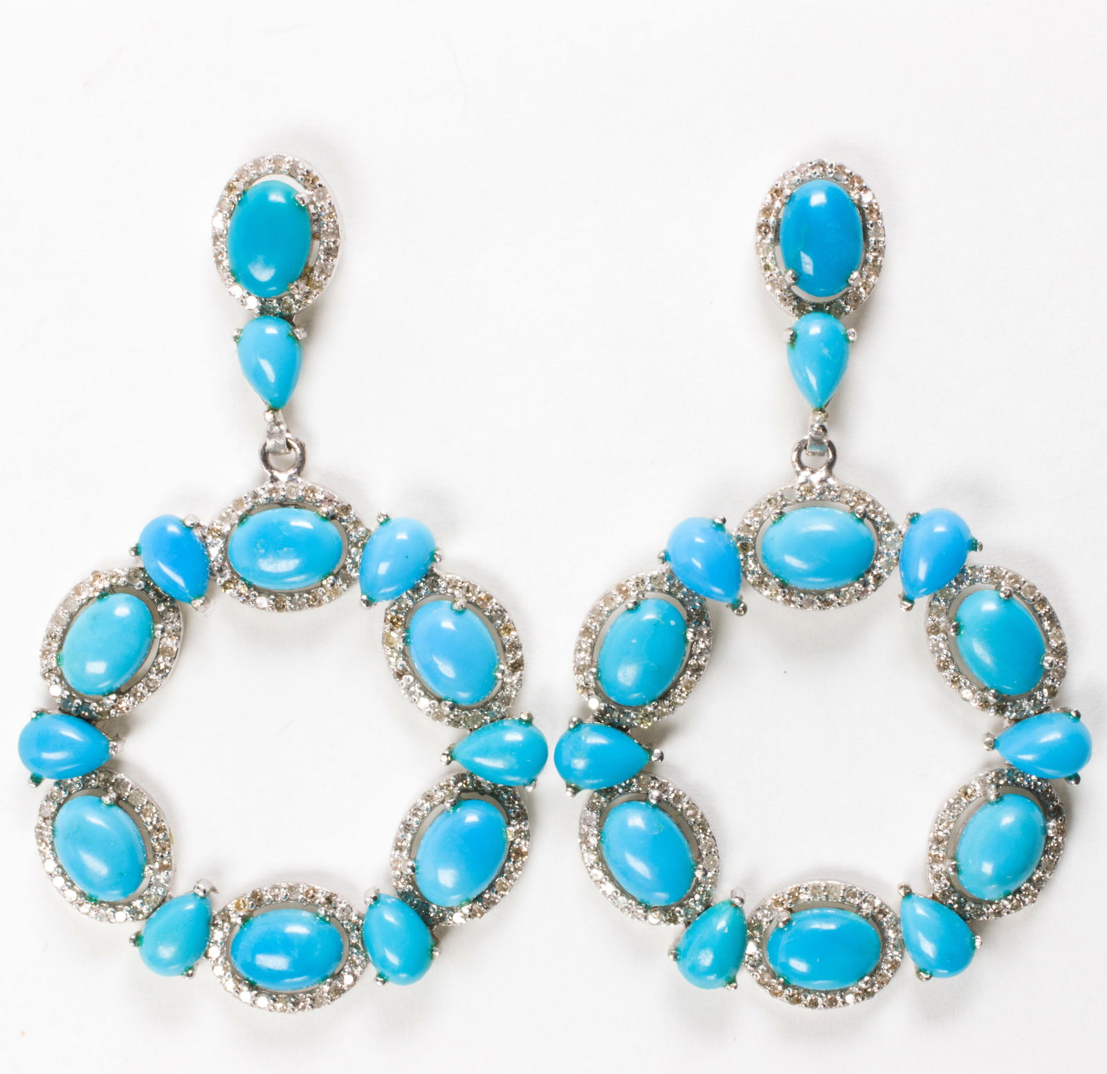 A pair of turquoise, diamond, and silver earrings: A pair of turquoise, diamond, and silver earringsDesigned with 12 oval and pear-cut turquoise cabochons, framed within halos of round brilliant-cut diamonds; total turquoise weight: 15.65; total