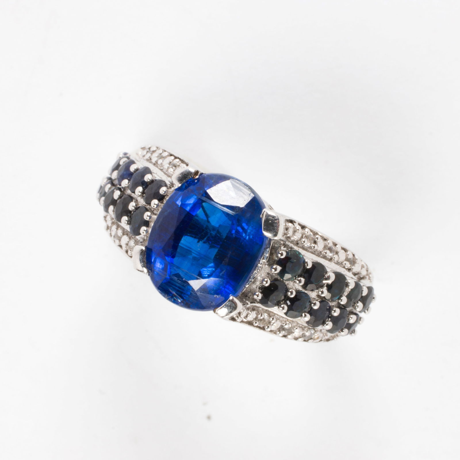 A sapphire, diamond, and sterling silver ring: A sapphire, diamond, and sterling silver ringCentering an oval-cut sapphire, framed on either side by rows of round-cut sapphires and round-cut diamonds; total sapphire weight: 3.00 grams; size 7;
