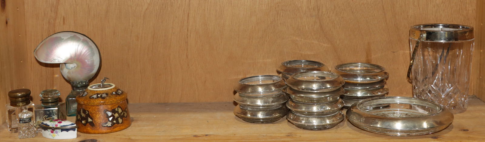 An assembled group of sterling mounted table and desk articles: An assembled group of sterling mounted table and desk articles, comprising (15) sterling mounted coasters, (1) ashtray, (1) wine cooler and (6) desk articles in shell, glass and turned wood, 1.75"h