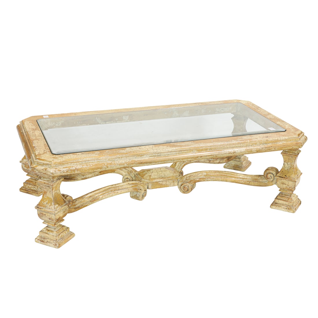 A large Italianate style coffee table: A large Italianate style coffee table, late 20th century, the distressed frame with a molded edge inset with a beveled glass top, raised on square baluster legs joined by scrolled stretchers; 19.5"h x