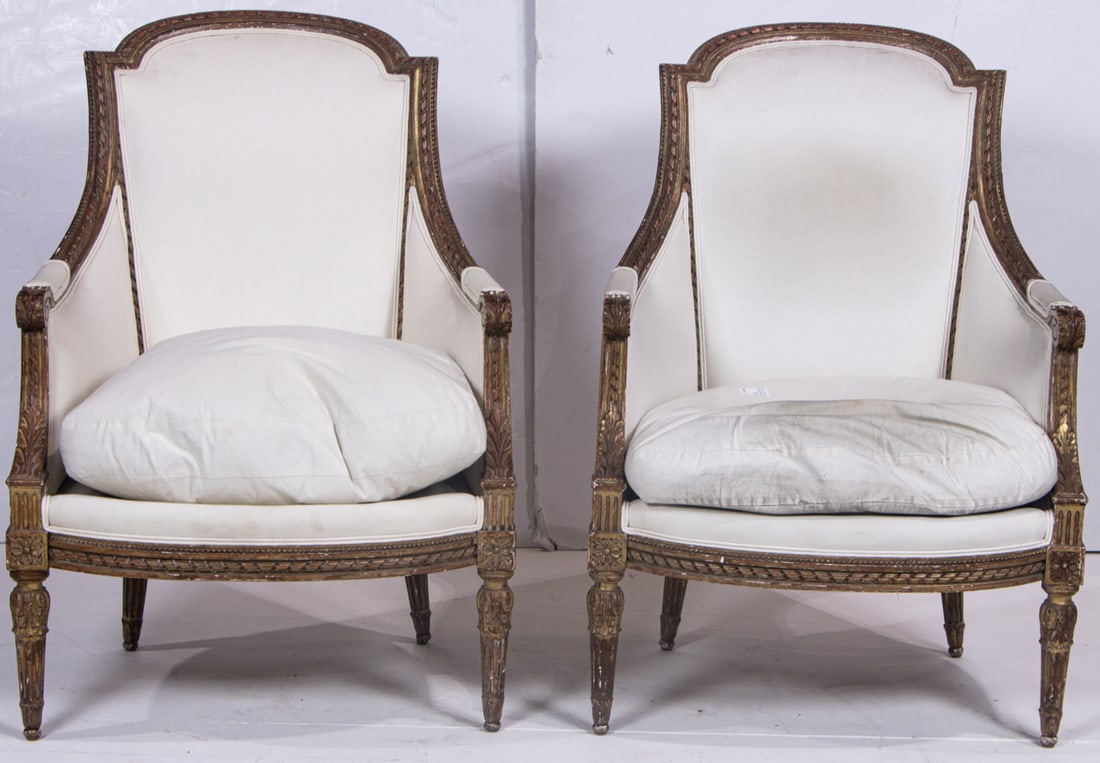 A pair of Louis XVI parcel giltwood bergeres: A pair of Louis XVI parcel giltwood bergeres, late 18th century, the arched backrest with closed sides, and loose seat cushion raised on leaf carved fluted legs, 38.5"h x 27"w x 24"d