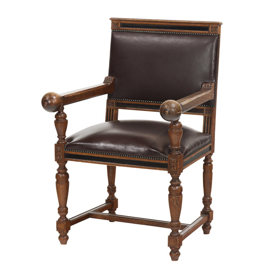 A Spanish Revival oak and leather armchair: A Spanish Revival oak and leather armchair, early 20th century, the square back issuing straight arms ending in ball handrests, the trapezoidal seat raised on turned legs joined by stretchers, 38.75"h