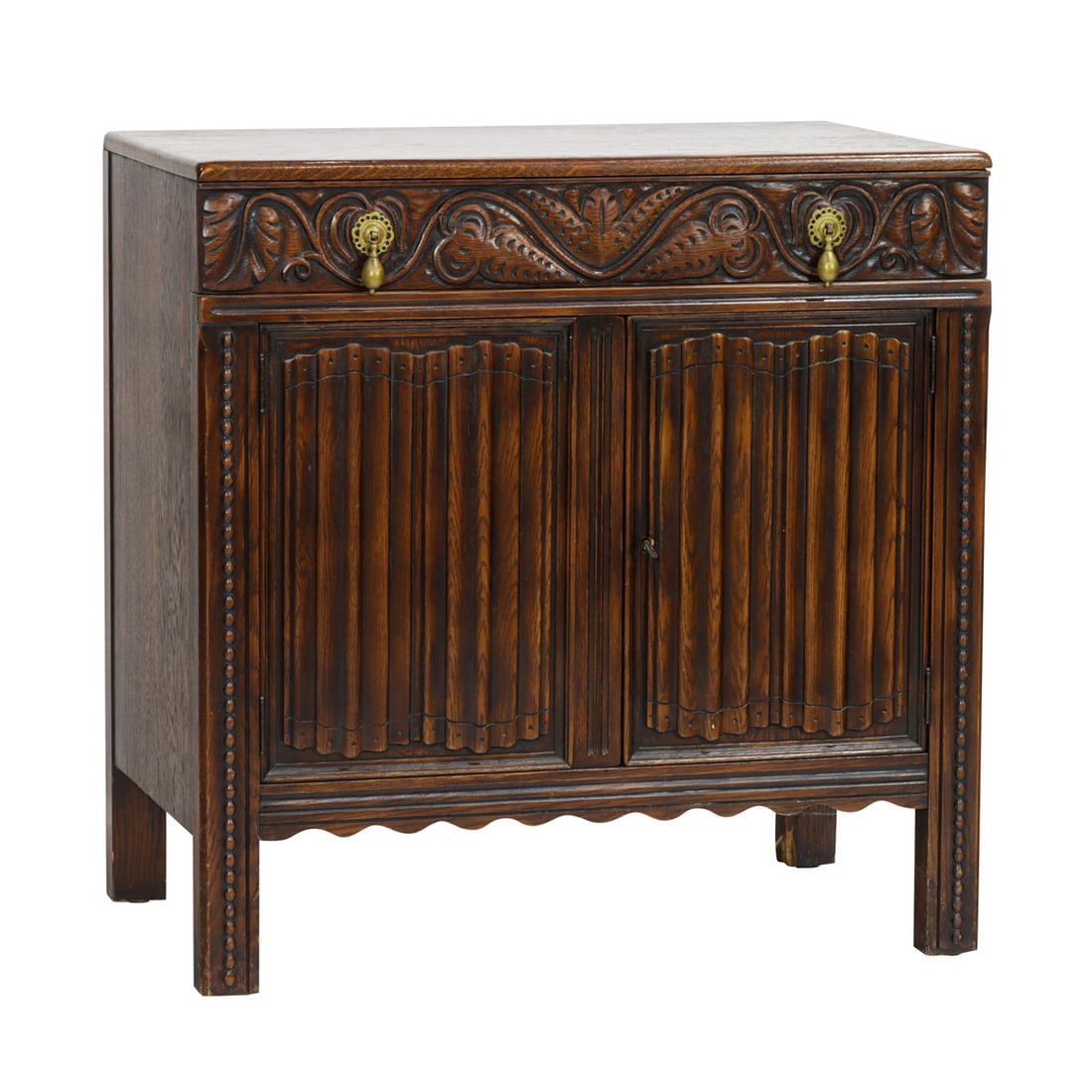A Jacobean Revival oak cabinet: A Jacobean Revival oak cabinet, The John Breuner Co. of San Francisco, early 20th century, the rectangular case with leaf carved drawer over two doors carved with linen fold panels, metal factory tag