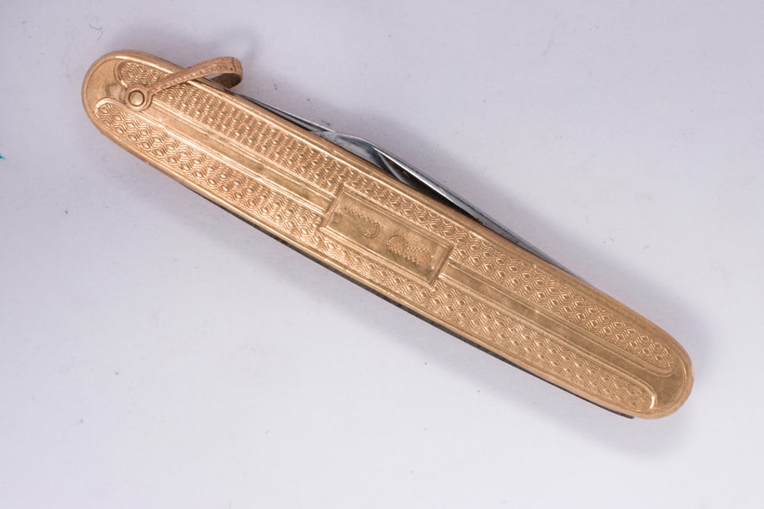 A 10k gold and stainless steel pocketknife: A 10k gold and stainless steel pocketknifeAccented by a repeating geometric pattern, with stainless steel blades; length: 2 1/2 in; 15.85 grams