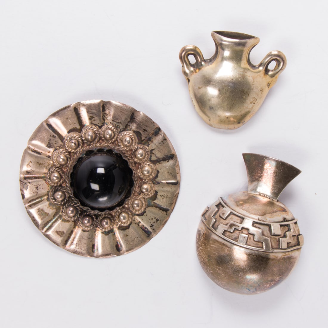 Three mexican silver art brooches: Three mexican silver art broochesTwo designed as vessels, together with one set with a round-shaped hardstone cabochon measuring 18.85 mm; lengths: 2, 1 1/4, and 2 1/4 in, respectively; gross weight: