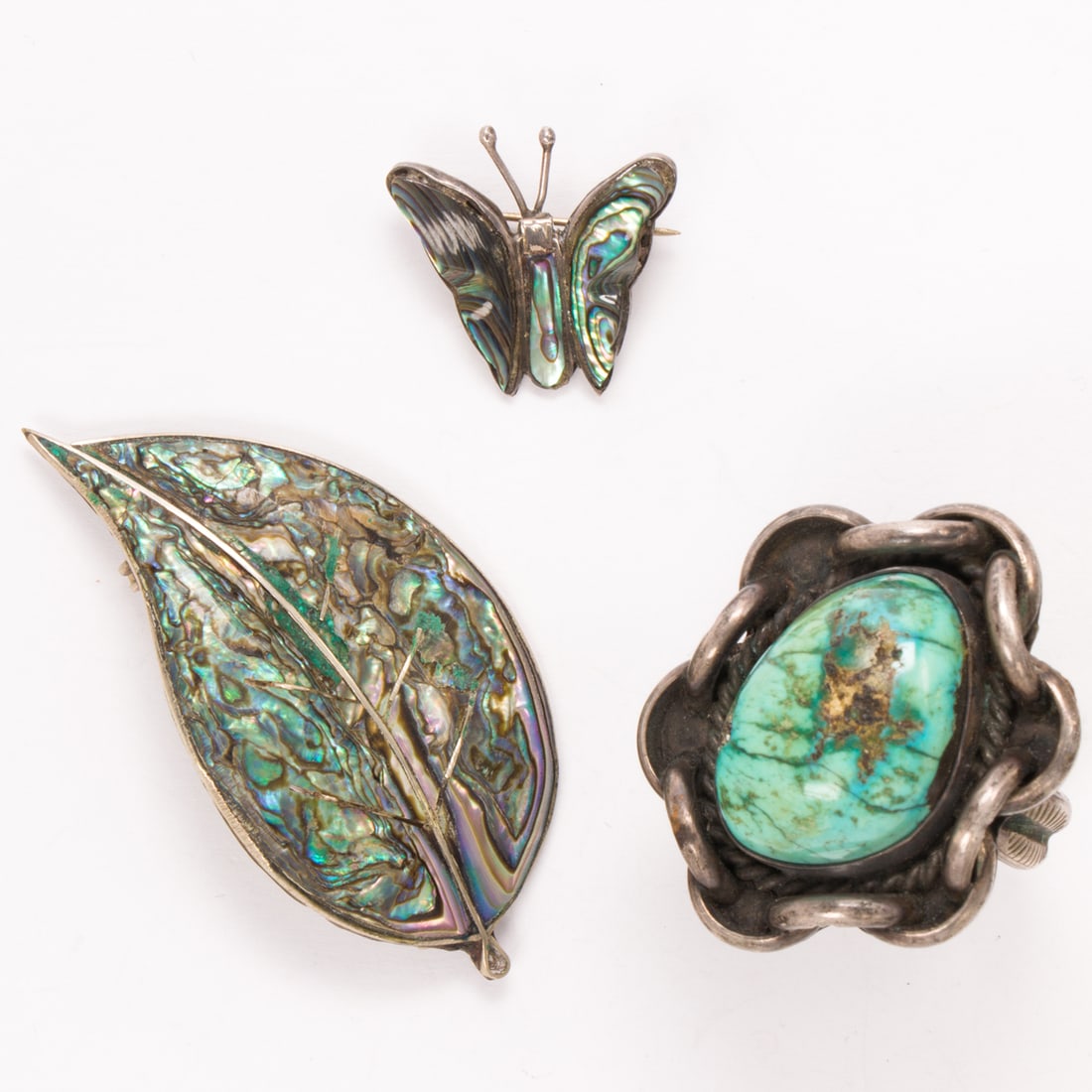 Three hardstone and silver jewelry items: Three hardstone and silver jewelry itemsComprising two brooches and one ring accented by abalone and turquoise, respectively; ring size: 12; gross weight: 33.25 grams