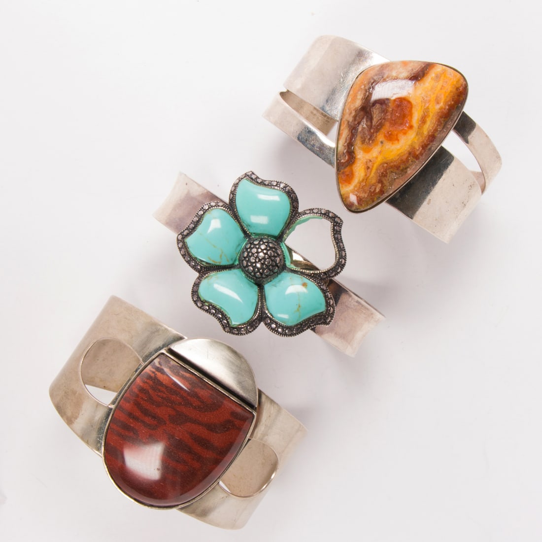 a group of silver and hardstone bangles: a group of silver and hardstone banglescomprising two Dessert Rose Trading braclelets set with petrified wood and agate; accompanied by one set with faux turquoise; 150.00 gross gramsCondition note: