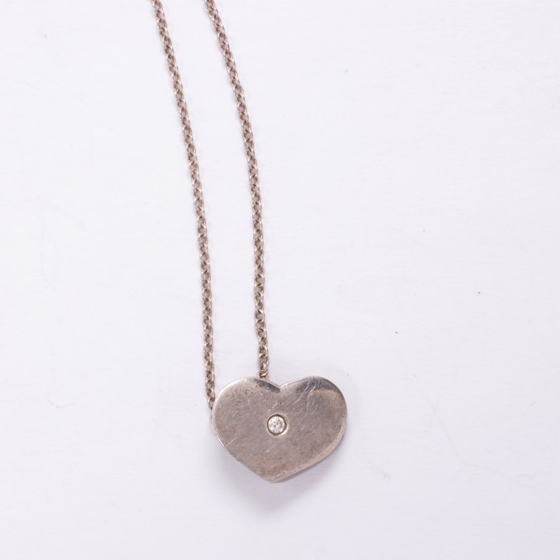 A vintage Elsa Peretti for Tiffany & Co. diamond and silver pendant necklace: A vintage Elsa Peretti for Tiffany & Co. diamond and silver pendant necklacedesigned as a heart centering a round brilliant-cut diamond, on original cable-link chain; 4.10 grams; pendant length: 1/2