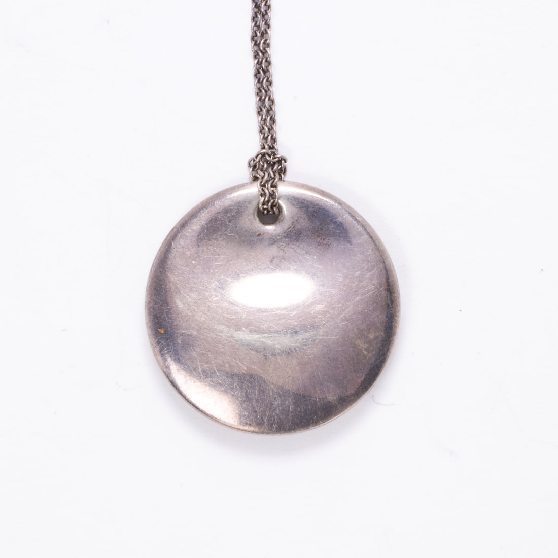 An Elsa Peretti for Tiffany & Co. sterling silver pendant necklace: An Elsa Peretti for Tiffany & Co. sterling silver pendant necklacethe disk pendant suspending from cable-link chain; 12.10 grams; pendant length: 7/8 in; chain length: 15 in