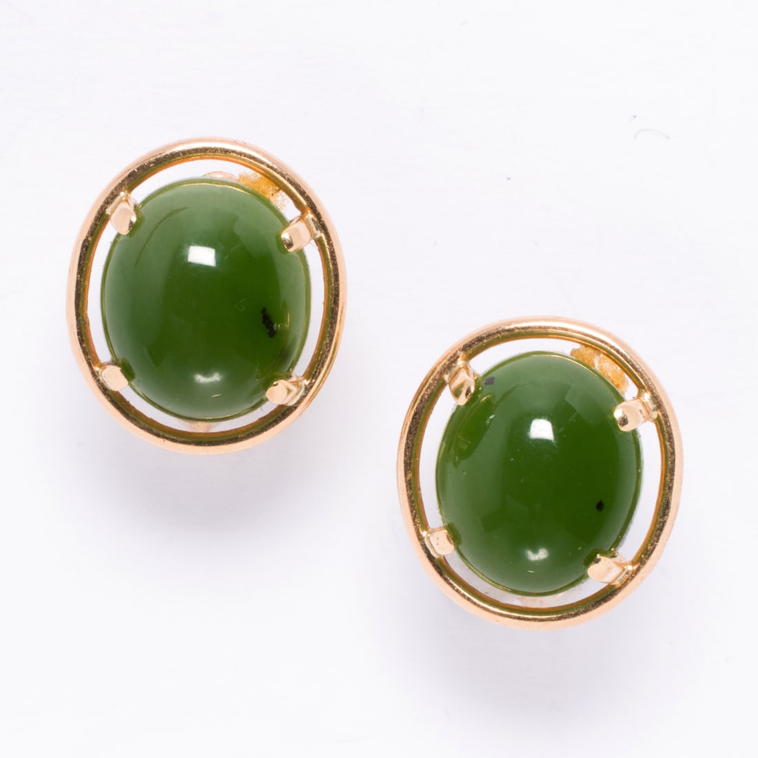 A pair of jade and 14k gold ear-clips: A pair of jade and 14k gold ear-clipsSet with oval-shaped jade cabochons measuring 14.04 x 12.04 mm, set within 14k gold; 9.05 grams
