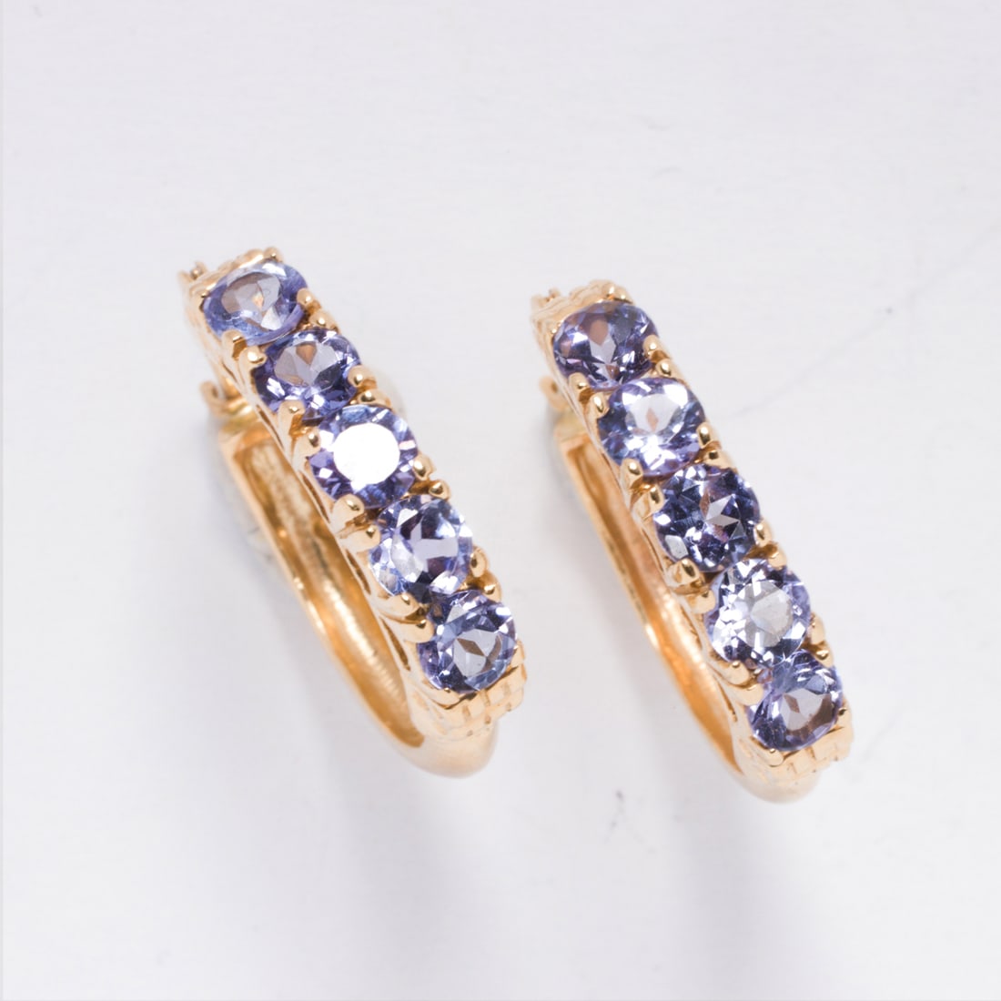 A pair of tanzanite and 14k gold hoop earrings: A pair of tanzanite and 14k gold hoop earringsDesigned with five round-cut tanzanite weighing a total of 1.30 carats; length: 3/4 in; 3.90 grams