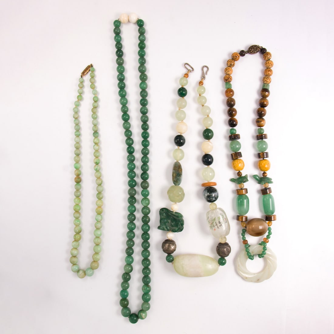 Four green hardstone beaded necklaces: Four green hardstone beaded necklacesComprising four hardstone beaded necklaces of varying materials including jade and tiger's eye; gross weight: 318.30 grams