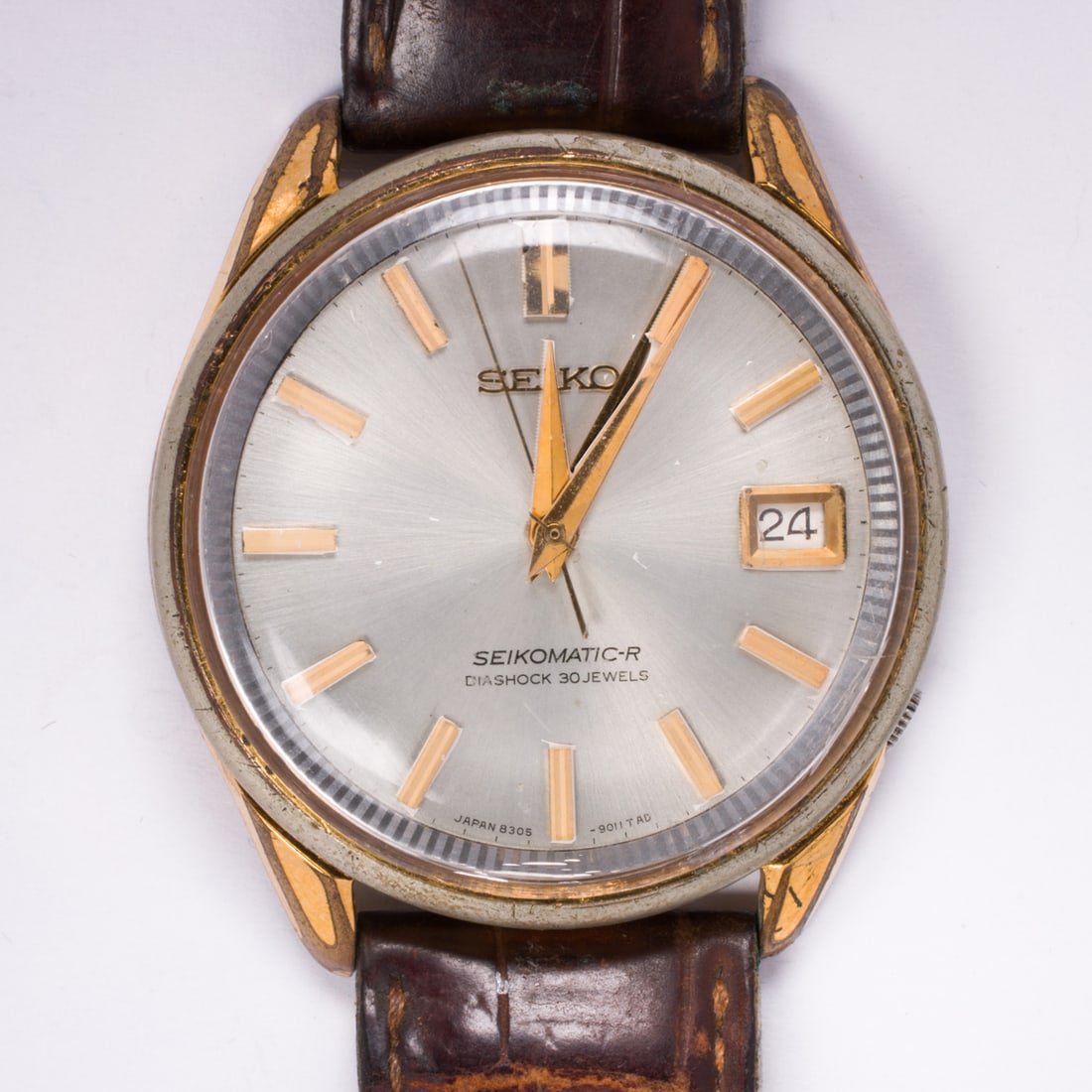 A Seiko Seikomatic watch: A Seiko Seikomatic watchThe champagne-tone face, gold-tone stick indices, gold-tone dauphine hands, within polished stainless steel case, containing manual movement, on brown leather strap; case