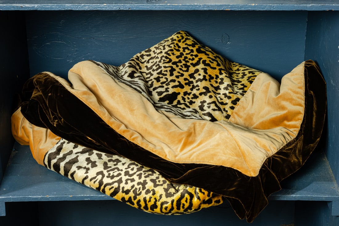 A faux leopard print velvet throw: A faux leopard print velvet throw, unmarked, backed in gold velvet, 88"l x 70.5"w, together with machine-made rug in rust and purple, 76"l x 48"w [2 total]