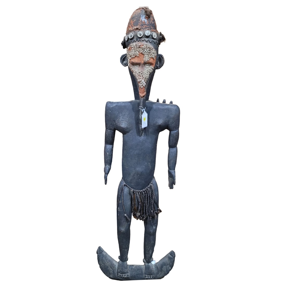 An Oceanic carved male figure: An Oceanic carved male figure, Papua New Guinea, decorated with Cowrie shells and standing on a boat, approx 50"h x 15"w