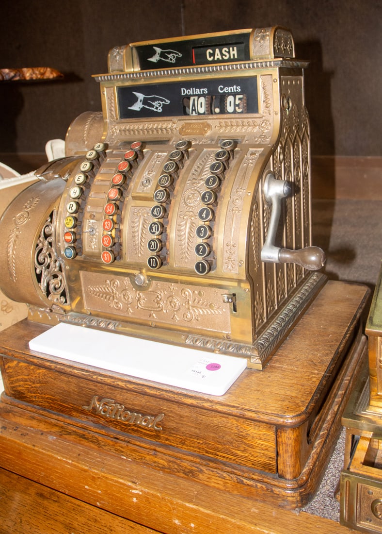 A National brass cash register on oak base: A National brass cash register on oak base, model 442-XX, serial no. 1542289, circa 1916, the ornate cast brass case with scrolling foliate motifs, the left side with a receipt printer and the right