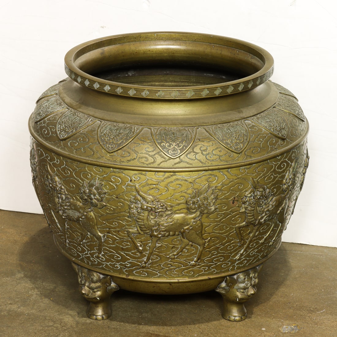 Japanese bronze tripod censer: Japanese bronze tripod censer. Cast with eight kirin on a cloud scroll ground, below a lappet band at the shoulder with stylized phoenixes, all raised on lion head supports, 13.5"h x 15"w.