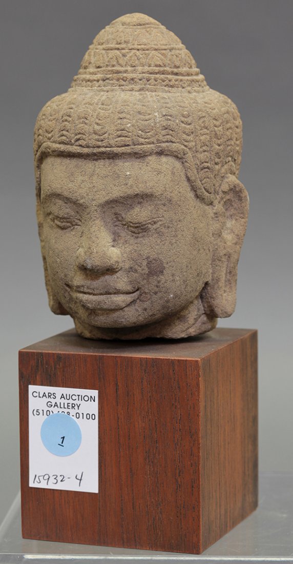 Khmer-style Stone Head: Cambodian Khmer-style stone head, with patterned hair in a top knot above the down cast eyes, lobed nose and full lips, with wood stand, stone: 5.6"h