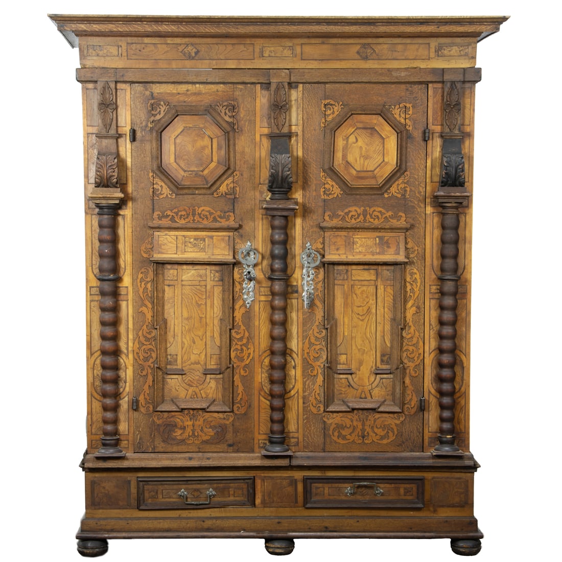 A German quartersawn oak Schrank or cabinet: A German quartersawn oak Schrank or cabinet, late 18th century, paneled doors with scrollwork and large twist carved supports, retains wrought hardware and key, 79.5"h x 65"w x 25"d