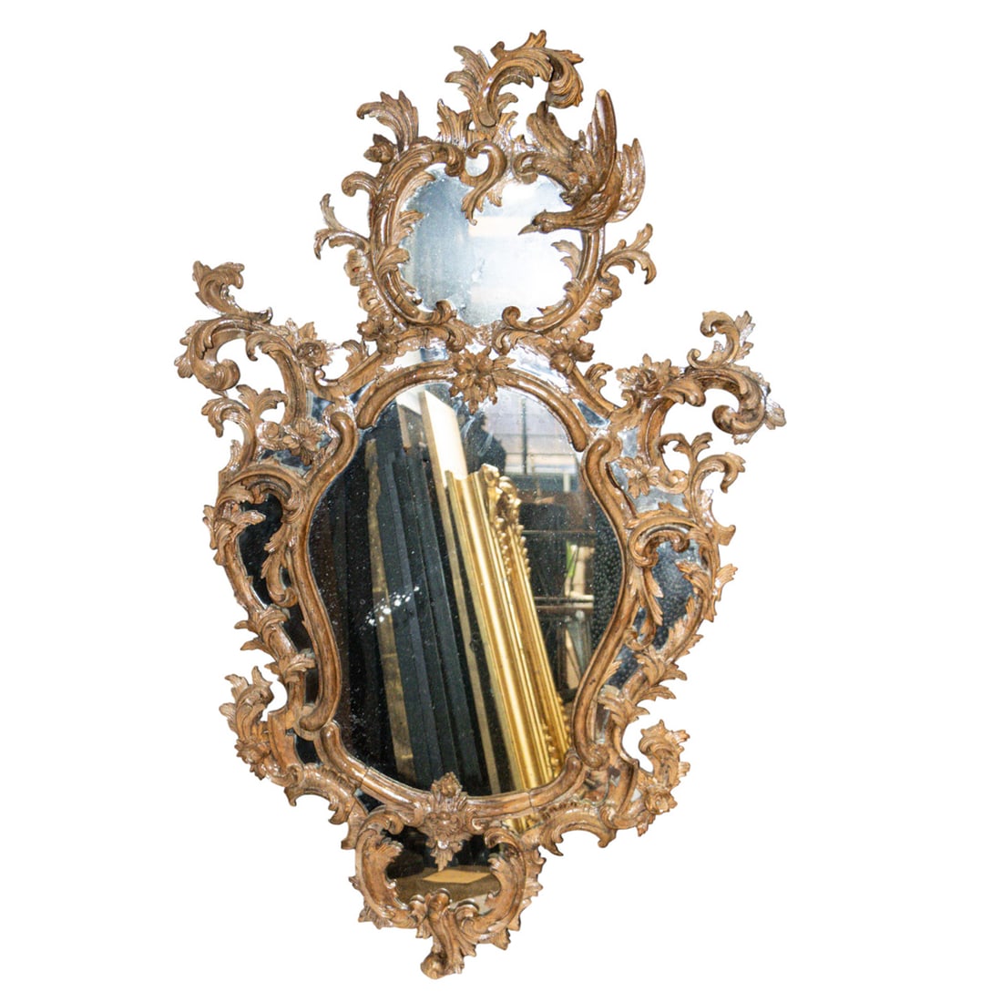 A Rococo carved wall mirror, 18th century: A Rococo carved wall mirror, second half 18th century, the mirrored plate within a pierced and carved frame of asymmetrical cartouche form incorporating hoho bird, C-scrolls, coquillage and floral spr