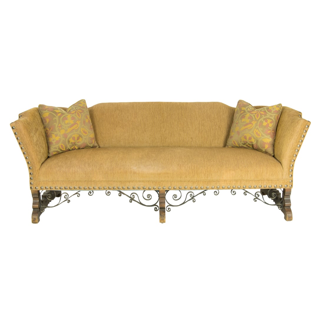 A Spanish Revival sofa circa 1920: A Spanish Revival sofa circa 1920, with textured fabric and a shaped back continuing to the outswept arms, all with large brass nail head trim, the base with hand wrought iron supports and rising on s