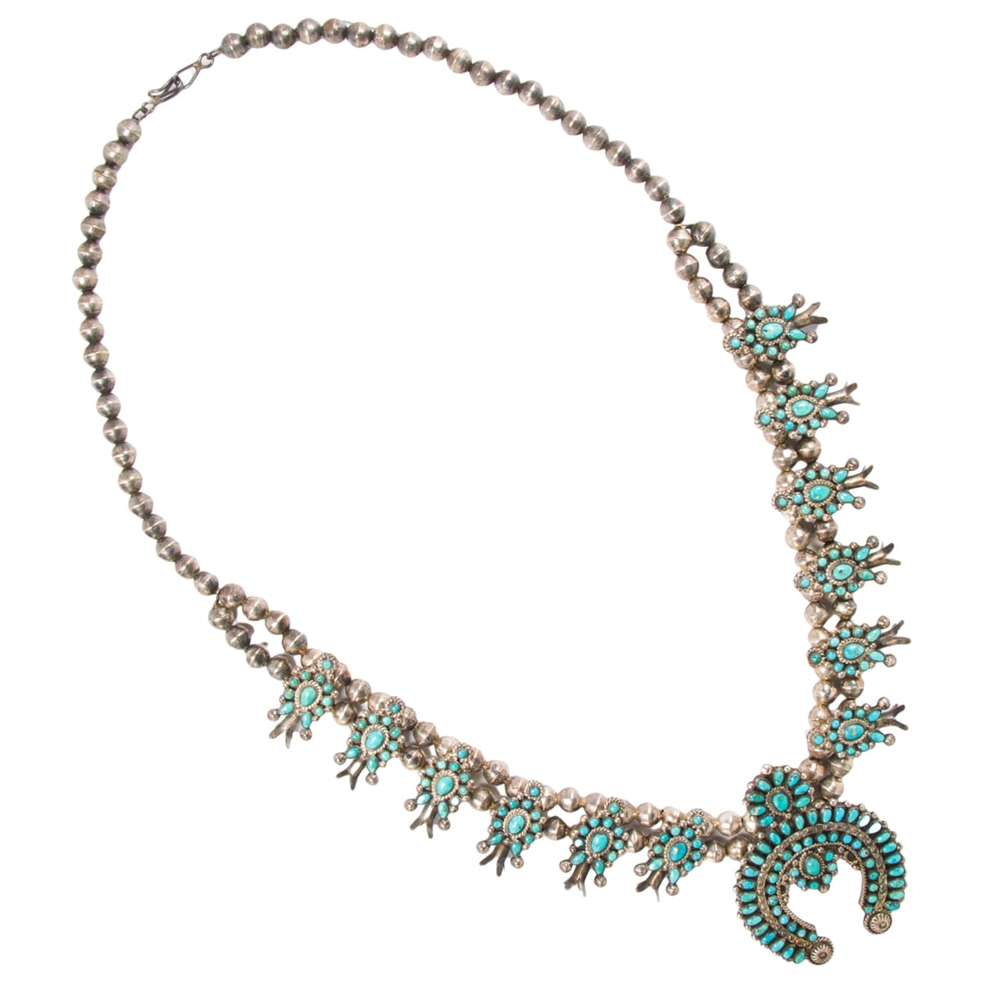 A Native American squash blossom necklace and pair of earrings: A Native American squash blossom necklace and pair of earrings Designed as a matching set, featuring numerous turquoise cabochons of varying shapes and sizes; necklace length: 28 in; earring length: