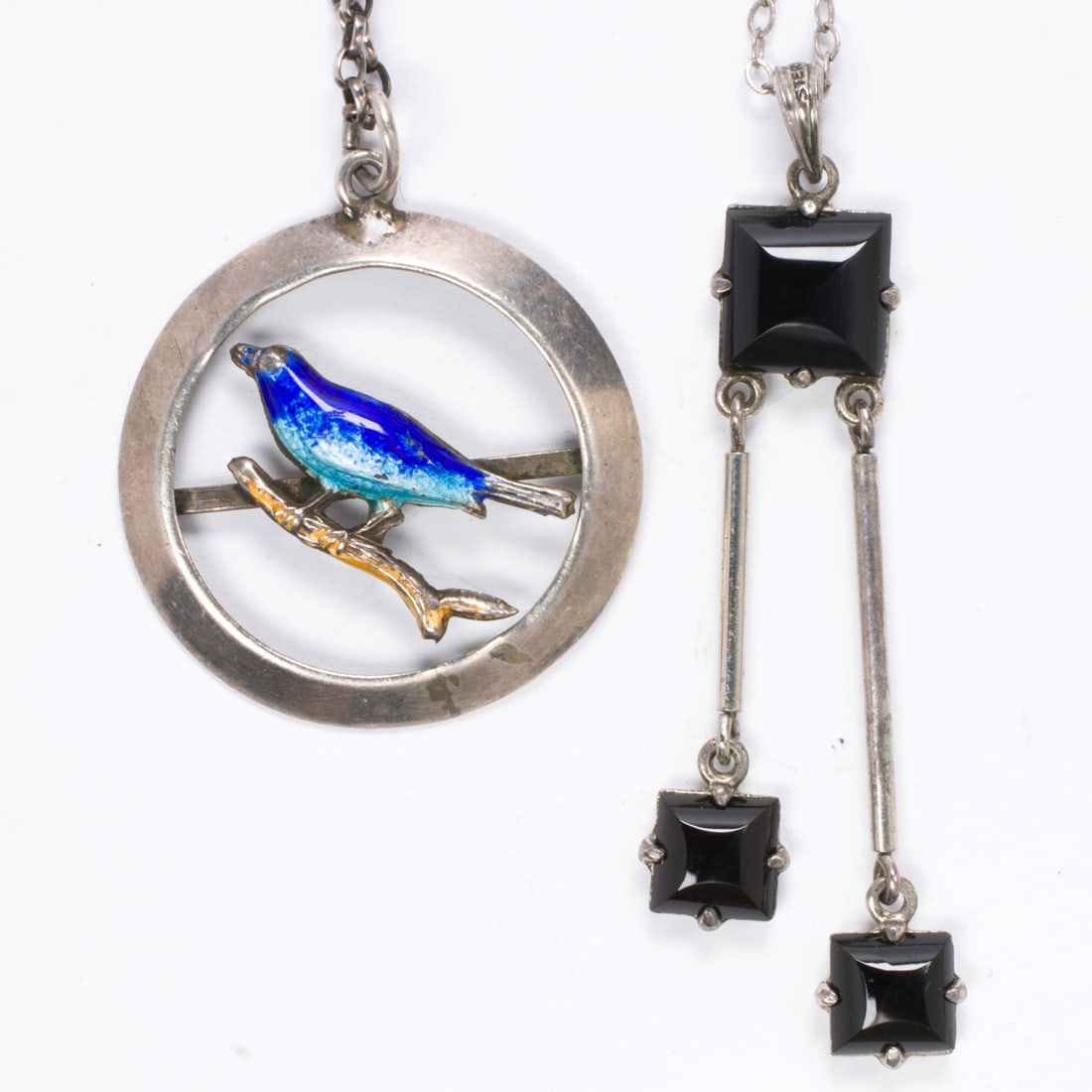 Two silver pendant necklaces: Two silver pendant necklaces Comprising one enameled bird pendant, together with a pendant set with three square-shaped onyx cabochons, on cable link chains; pendant lengths: 1 1/4 and 1 7/8 in, respe