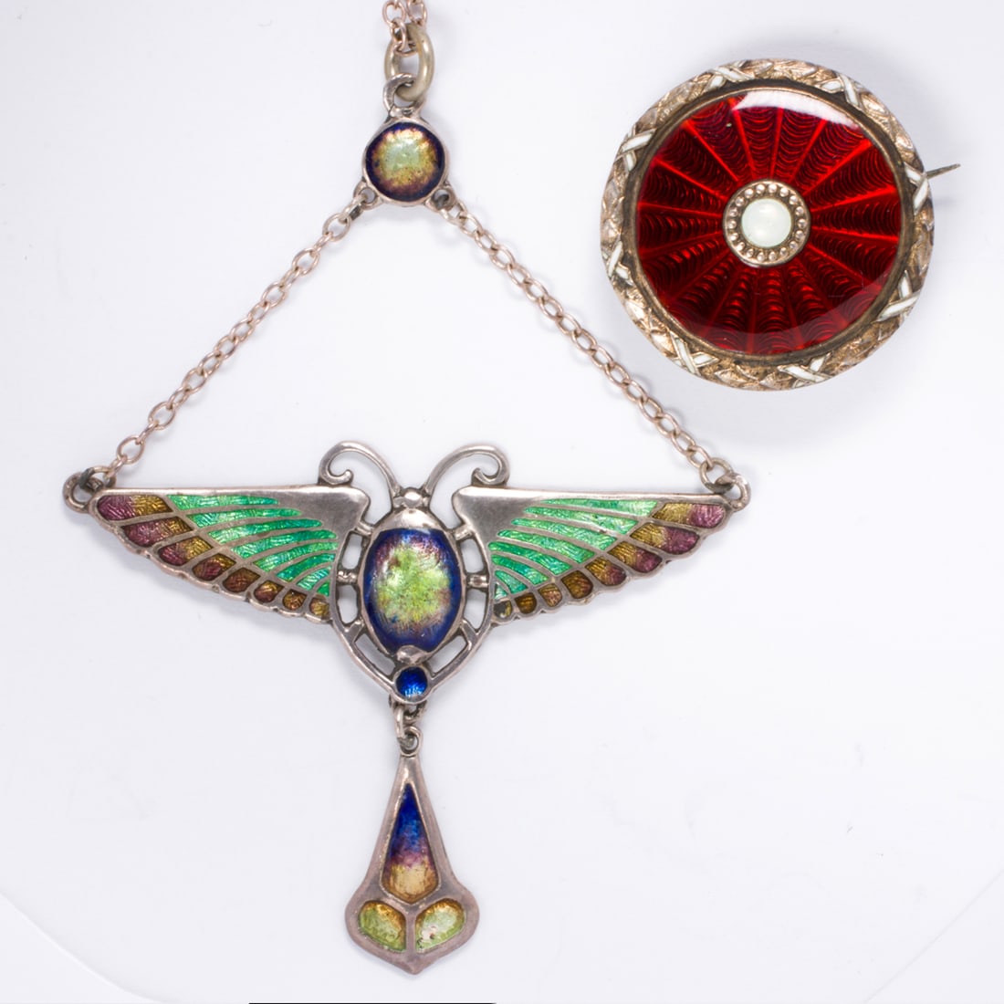 Two pieces of silver and enamel jewelry: Two pieces of silver and enamel jewelry Comprising one red guilloche enamel pin and one Art Nouveau Egyptian revival enameled scarab necklace; pin width: 7/8 in; necklace length: 16 in; gross weight: 
