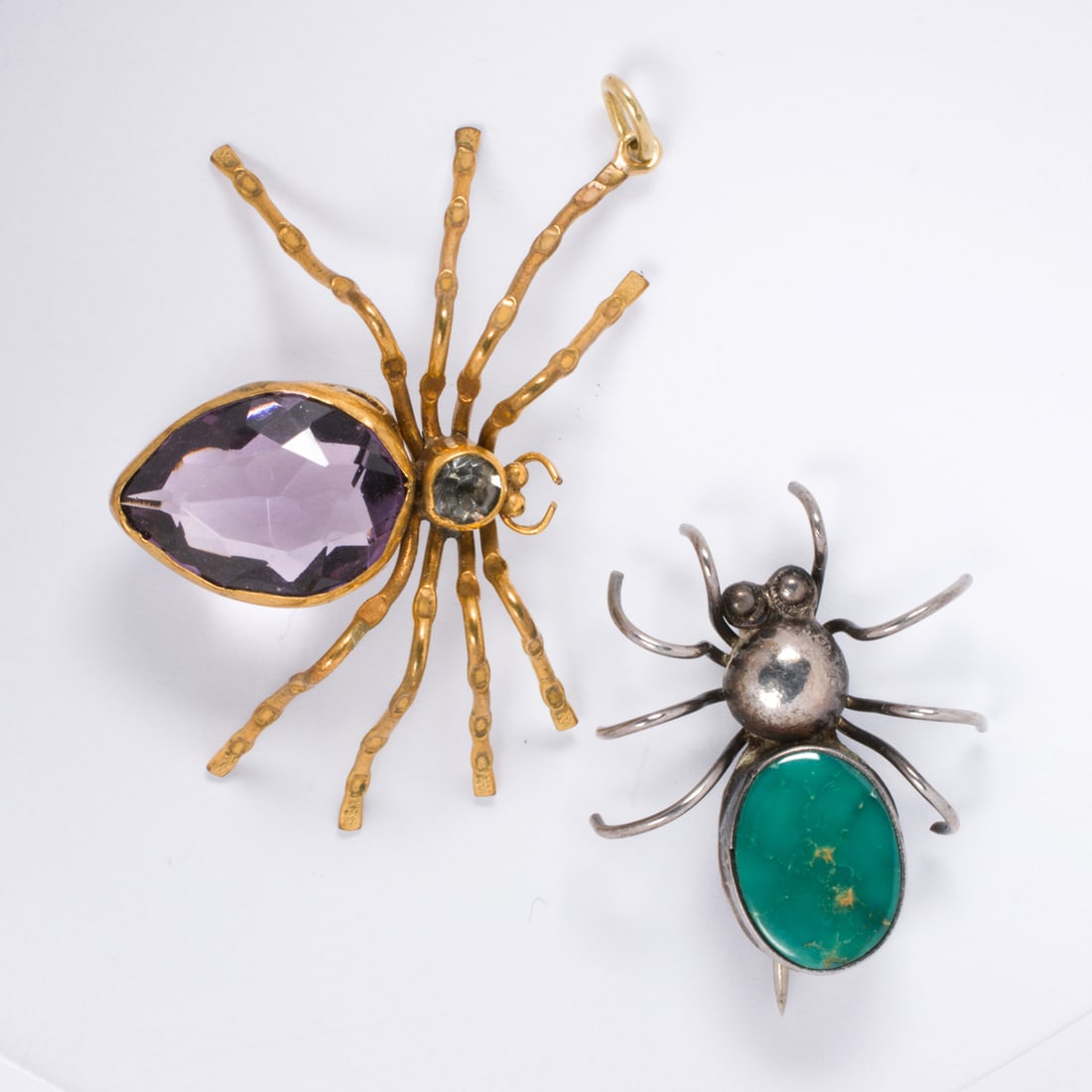 Two pieces of spider jewelry: Two pieces of spider jewelry Comprising one silver and hardstone spider pin and one gold-filled pendant set with glass stones; pin length: 1 1/2 in; pendant length: 1 3/4 in; gross weight: 8.00 grams