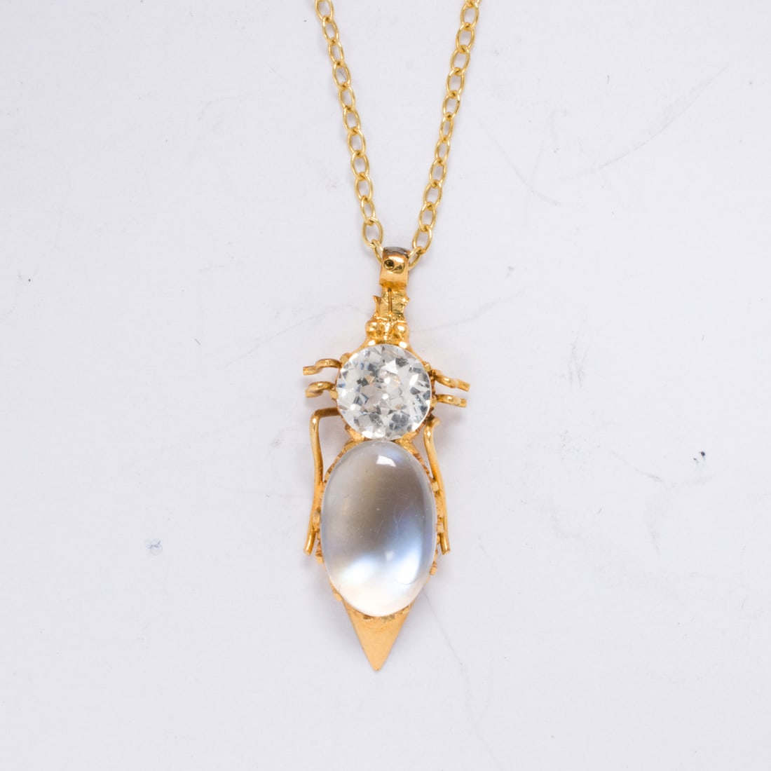 A sapphire, moonstone, and 10k gold necklace: A sapphire, moonstone, and 10k gold necklace Designed as an insect, set with a round-cut white sapphire weighing approximately 0.50 carat and a moonstone cabochon measuring 5.49 x 6.04 mm; pendant